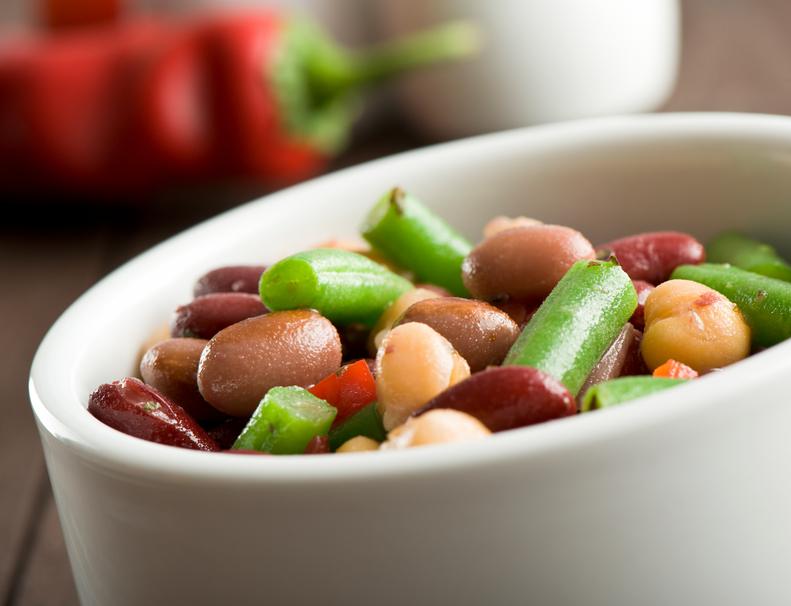 Colorful mixed beans salad in a white bowl. More salads...